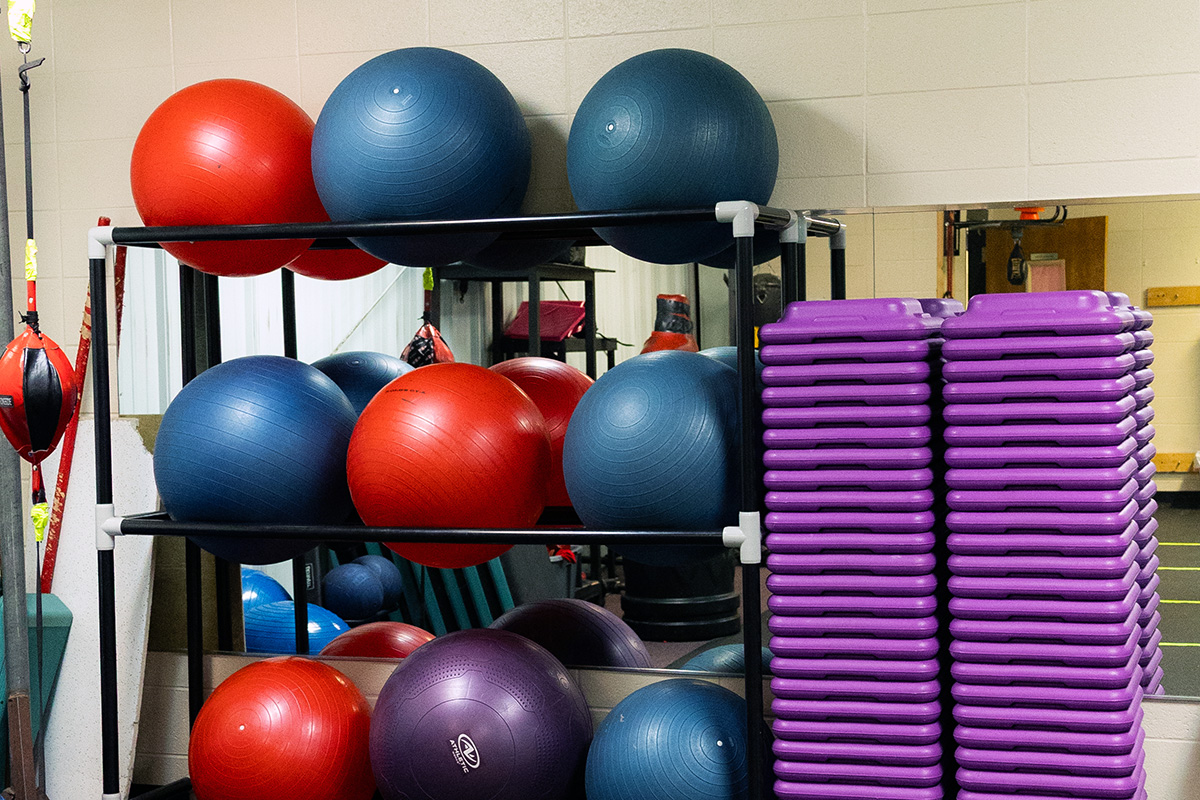 decfdb1f76a83e7c3bba7d6040e5b2dd Children playing basketball in a gym, with two players in red jerseys jumping to reach the ball and two others in purple jerseys actively participating. The YMCA logo is visible in the background, highlighting the community sports environment.